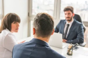 A man and woman discussing in an office, with a man on the other side of the table.
