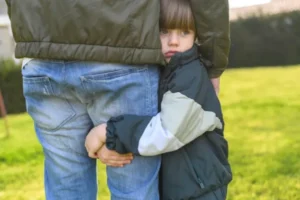 A man and a child standing in the grass, enjoying a peaceful moment together.
