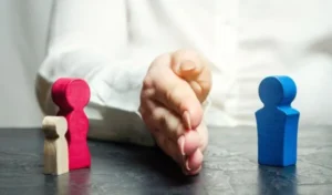 A person's hand separating a family of wooden figure
