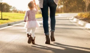 A woman and a little girl walking down a road.