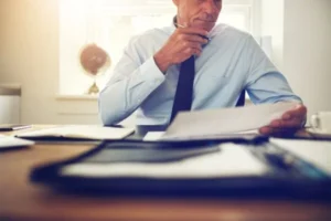 A man in a suit writing on a piece of paper.