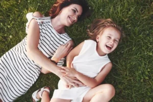 A woman and a little girl enjoying a peaceful moment as they lie down on the grass together.