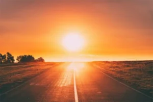 A scenic road stretching towards the radiant sun.
