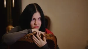 A woman with black hair sitting on a chair.