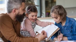 A man and two children sitting at a table and drawing on a paper.