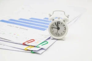 Clock and papers on desk with clips.