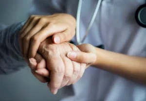 A doctor holding the hand of an elderly person