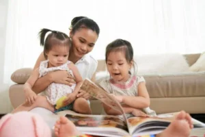 A woman and two children engrossed in a book, sharing a moment of learning and connection.