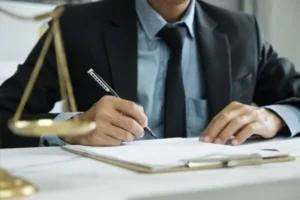 A man in a suit writing on a paper with a pen.