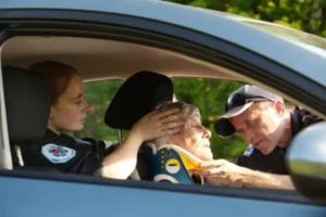 A police officer assisting an elderly woman in a car