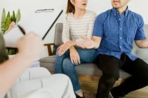 A couple conversing with a therapist while seated on a couch.