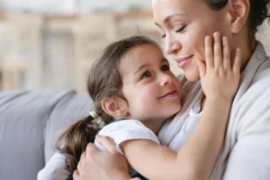 A woman and a little girl sharing a warm embrace on a cozy couch.