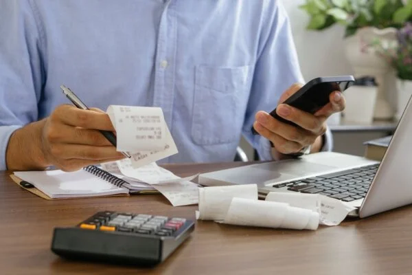 Image of person multitasking with phone, paper, and pen.