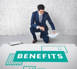 A focused man working while reviewing a paper and a graphic illustration labeled 'benefits.'