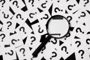 Magnifying glass on pile of question marks