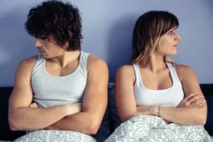 Married couple sitting in bed and not talking to each other