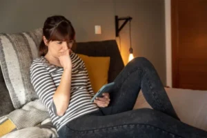 A girl is looking at her phone with a concerned expression.