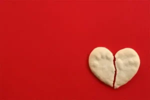 A broken heart-shaped cookie on a red background