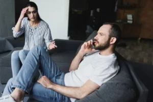 A man is on the phone while a woman is speaking to him.