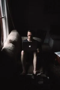 A man sitting on a couch with a laptop, engrossed in his work.