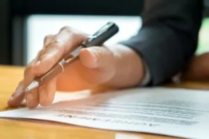 A man holding a pen while carefully reading the documents to sign