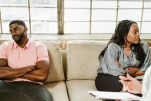 A couple is sitting on the sofa without talking to each other.