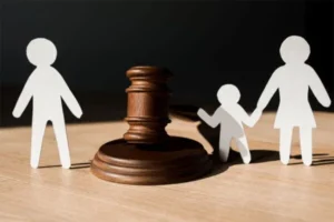 A paper cutout of a family is divided by a gavel placed on the table