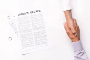 A couple shakes hands with wedding rings visible, alongside Divorce Decree documents