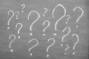 A chalkboard covered in question marks.