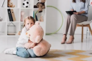 A young girl hugging her teddy bear tightly.