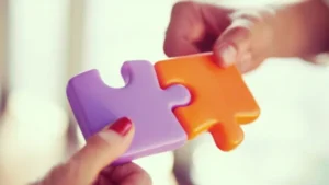 A couple's hands are putting together a puzzle