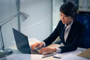 A girl in a corporate suit using her laptop while working.
