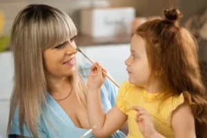 "A little girl brushes her mother's face gently